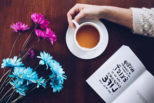 coffee cup person holding mug beside flowers book